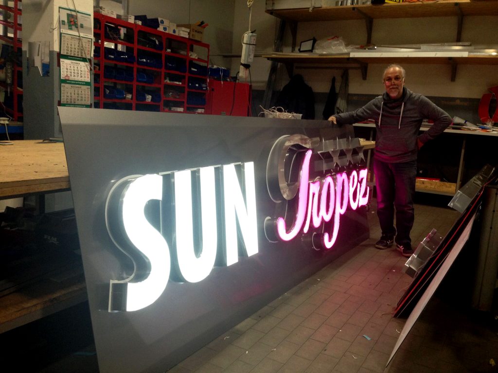 SUN TROPEZ Logo Leuchtreklame Detail bei Tag, markantes Designelement.